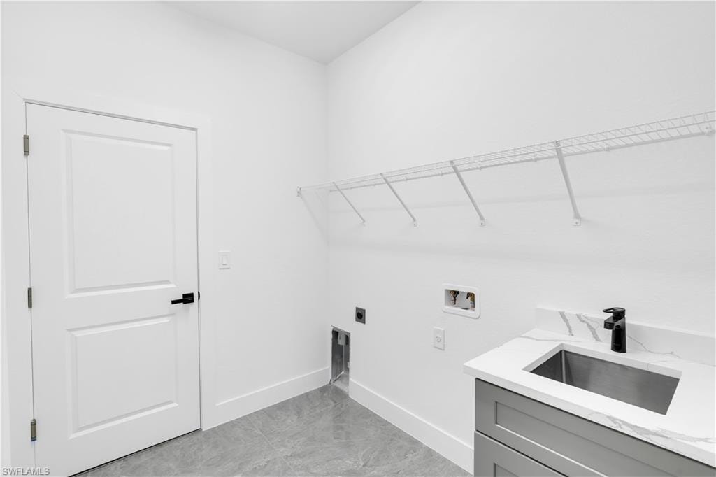 Laundry area featuring a utility sink with a matte black faucet, grey cabinetry, and white countertop with veining