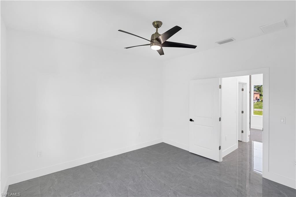 Spacious room featuring large format grey tile flooring, bright white walls, and a contemporary ceiling fan with integrated lighting