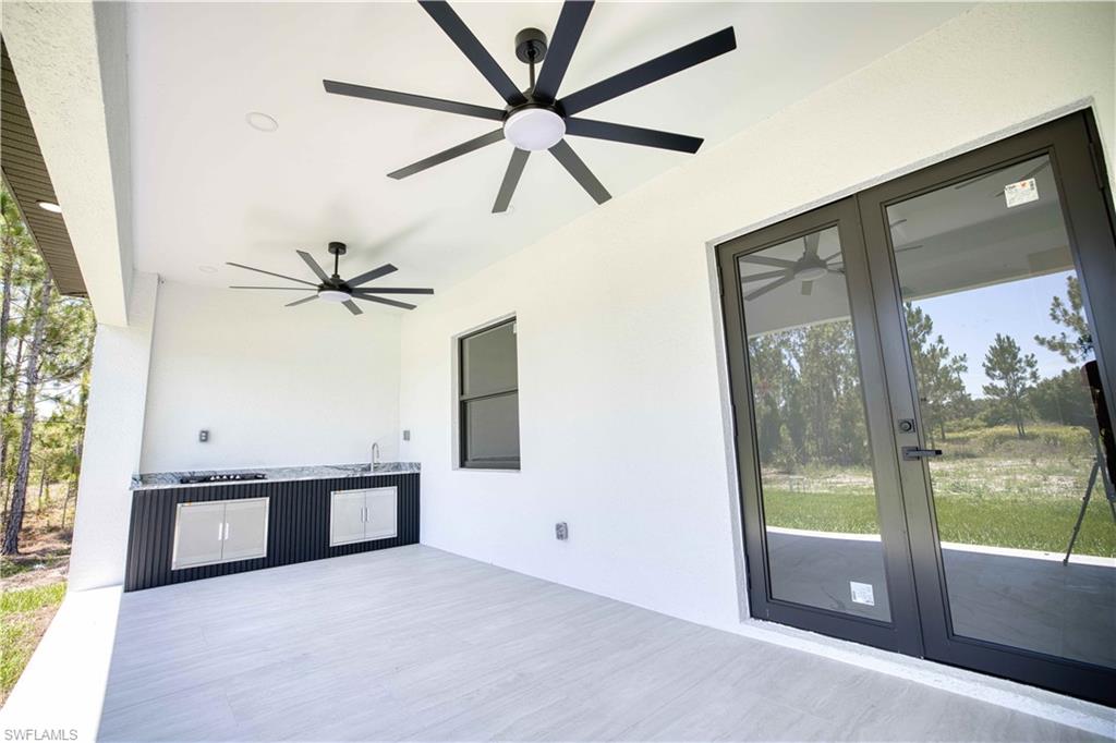 Covered patio featuring two black ceiling fans with integrated lighting