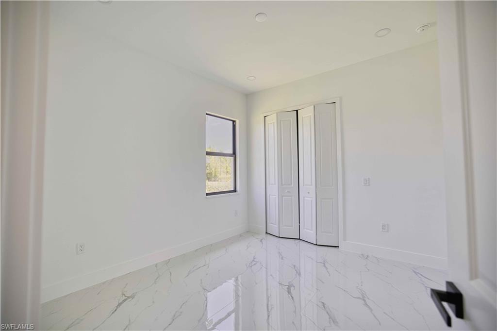 Bright interior space featuring white walls and marble-look tile flooring