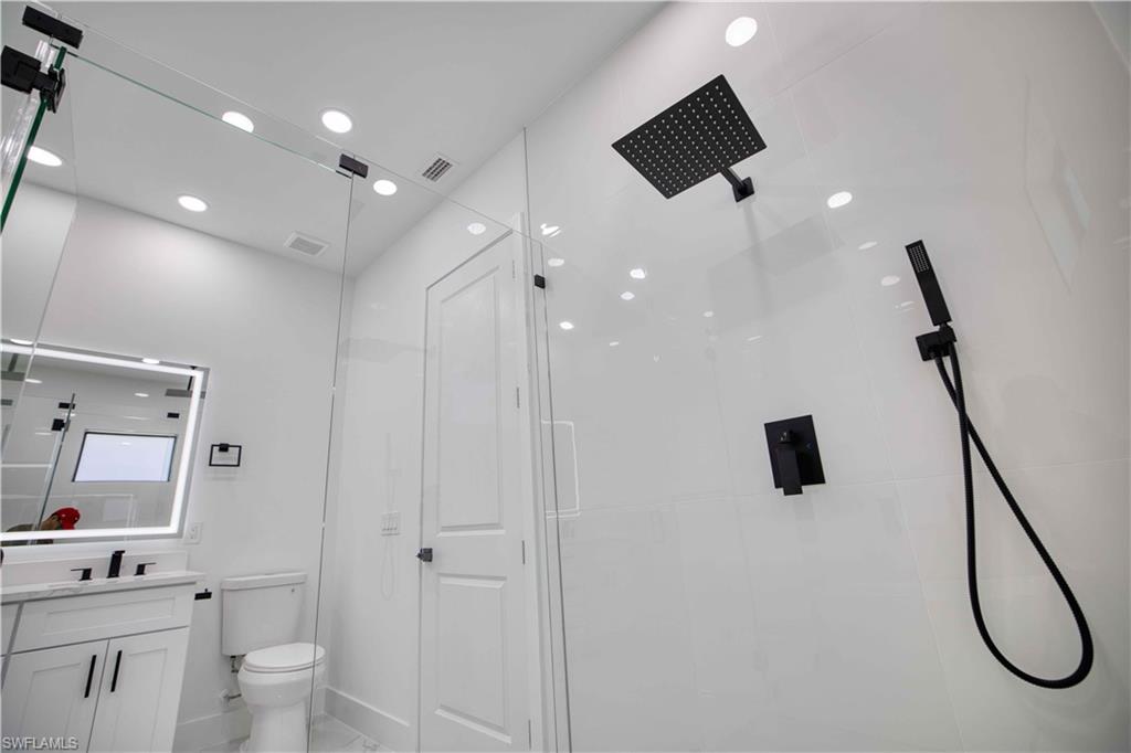 Modern bathroom featuring a frameless glass shower enclosure with matte black fixtures