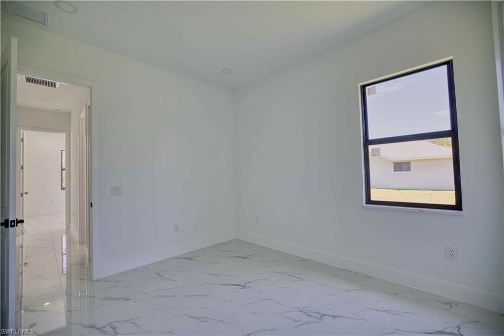 Spacious room featuring large format marble-look tile flooring, white baseboards, and a single black-framed window