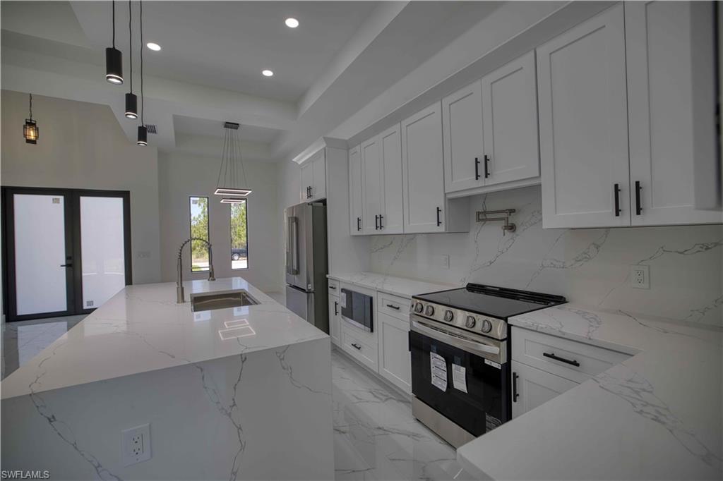 Modern kitchen featuring a large island with an undermount sink, white cabinetry with black hardware, stainless steel appliances, and a matching countertop and backsplash