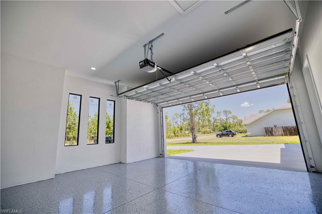 Spacious garage featuring a durable epoxy-coated floor, bright white walls, and a large overhead door