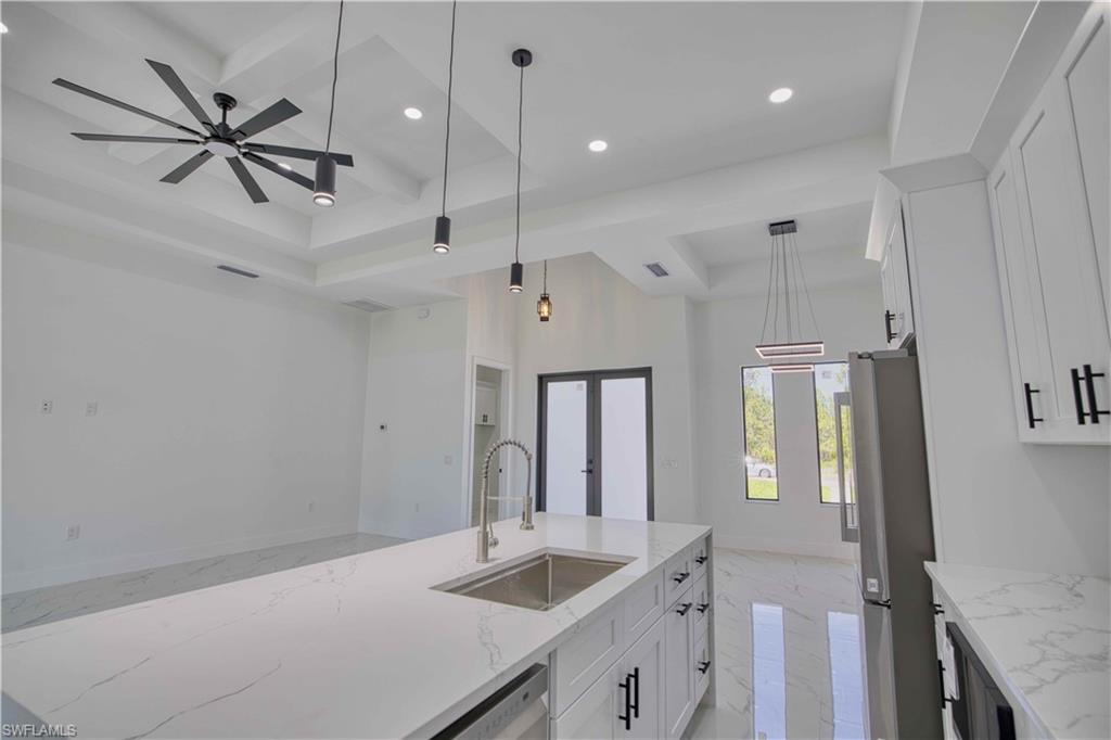 Kitchen island featuring an undermount sink, gooseneck faucet, and light-toned countertop