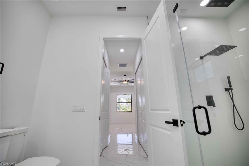 Walk-in shower featuring a glass enclosure and matte black rain showerhead, handheld shower, and fixtures