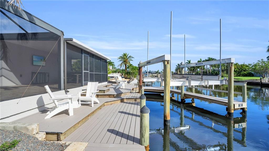 View of dock featuring a panoramic caged lanai, two level dock side patio  and a water view         VIRTUALLY ENHANCED -