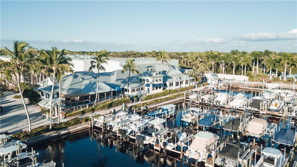 Waterfront property featuring a marina with multiple boat slips, a large commercial-style building with a multi-gabled roof, and extensive tropical landscaping