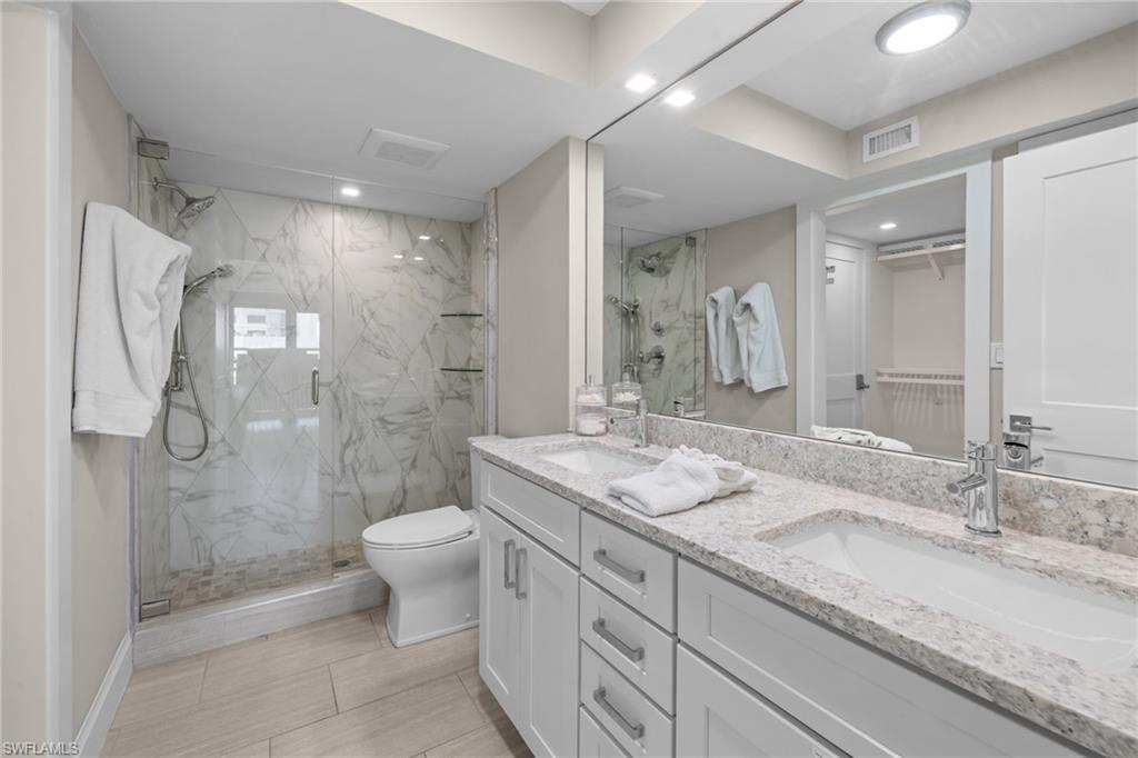 Spacious bathroom featuring a dual vanity with undermount sinks, granite countertops, and white shaker-style cabinetry