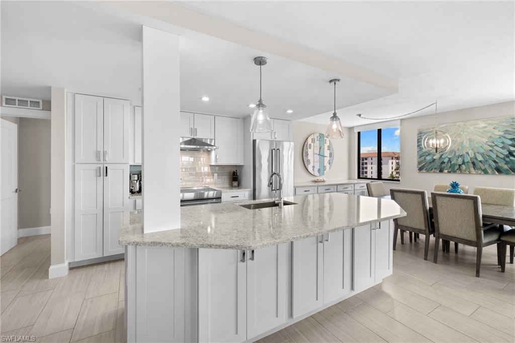 Kitchen island featuring a light-toned countertop, sink with a gooseneck faucet, and integrated storage cabinetry