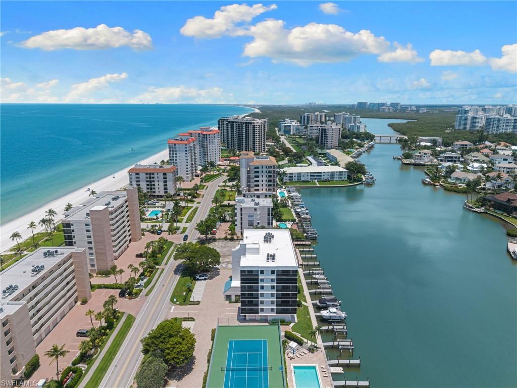Coastal residential area featuring beachfront buildings, a wide sandy beach, and a waterway with boat docks