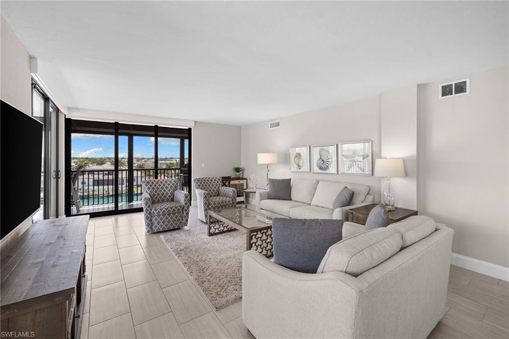 Living area featuring tile flooring, neutral wall tones, and a balcony with water views