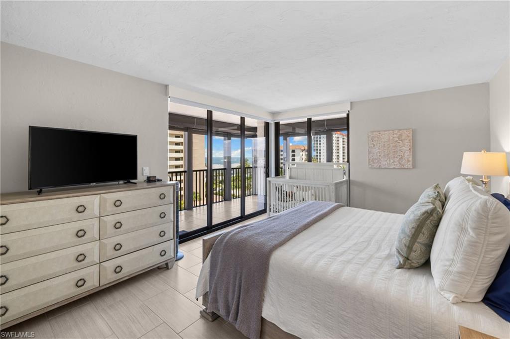 Spacious bedroom featuring light-toned walls, wood-finish flooring, and a full wall of sliding glass doors opening to a balcony