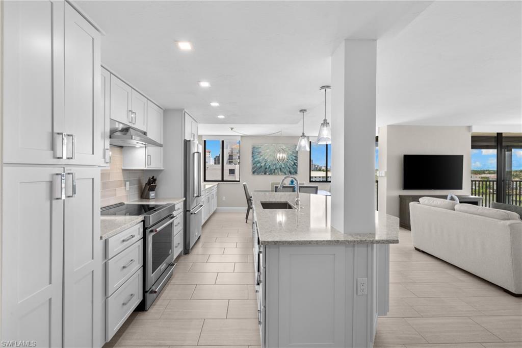 Contemporary kitchen featuring white shaker cabinetry, stainless steel appliances, light-toned countertops, and a tile backsplash