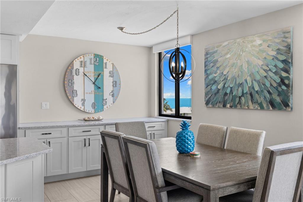 Dining area featuring a contemporary dark wood-finish dining table and upholstered chairs, a modern spherical chandelier, light-toned wood-finish flooring, and built-in cabinetry with light granite-style countertops