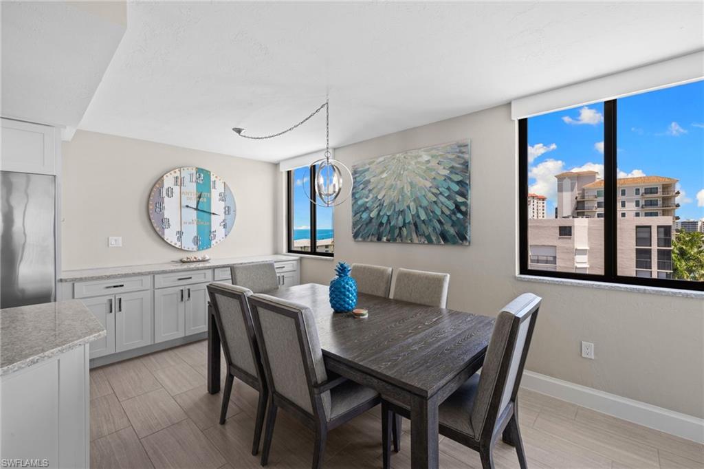 Dining area featuring wood-finish flooring, built-in cabinetry with granite-style countertops, and expansive windows offering distant water and city views