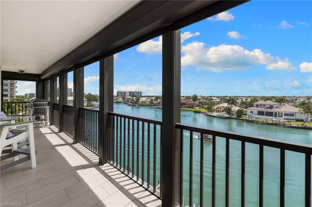 Expansive balcony featuring a water view, black metal railings, and light-toned tile flooring