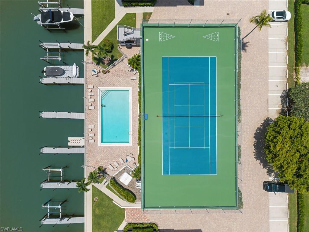 Community amenities featuring a tennis court, swimming pool, boat slips, and shuffleboard courts, surrounded by paved walkways and landscaped grounds