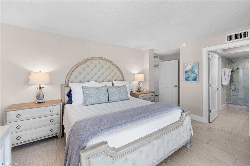 Spacious bedroom featuring light-toned walls, wood-finish flooring, and a shower with tiled walls