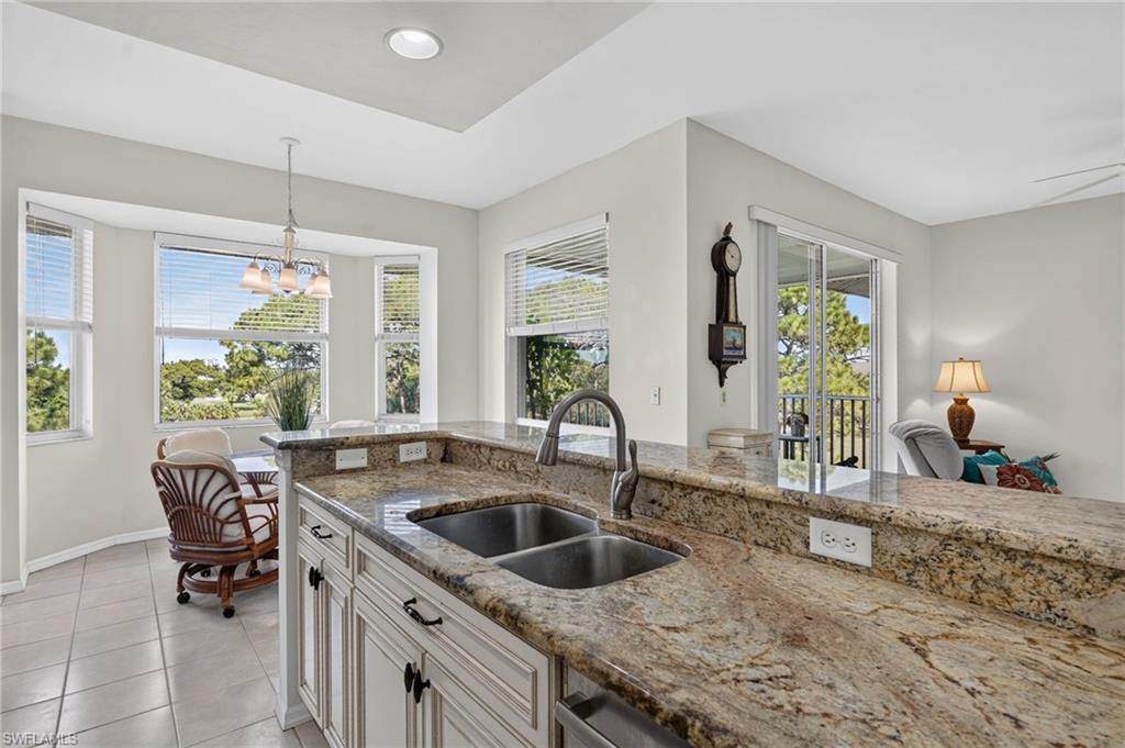Kitchen featuring granite countertops, a double basin stainless steel sink, and white cabinetry with dark hardware