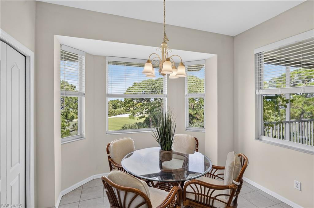 Dining area featuring a bay window with multiple windows, a chandelier, and tile flooring