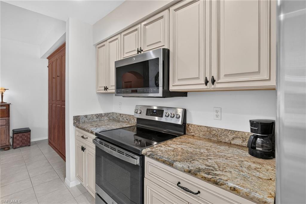 Kitchen featuring granite countertops, painted cabinetry, stainless steel oven, and an over-the-range microwave