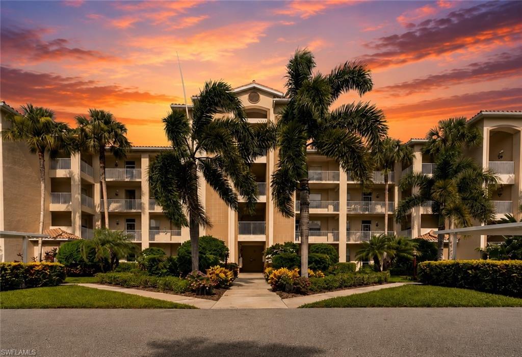 Multi-story building featuring stucco exterior, multiple private balconies with railings, and a prominent arched entryway