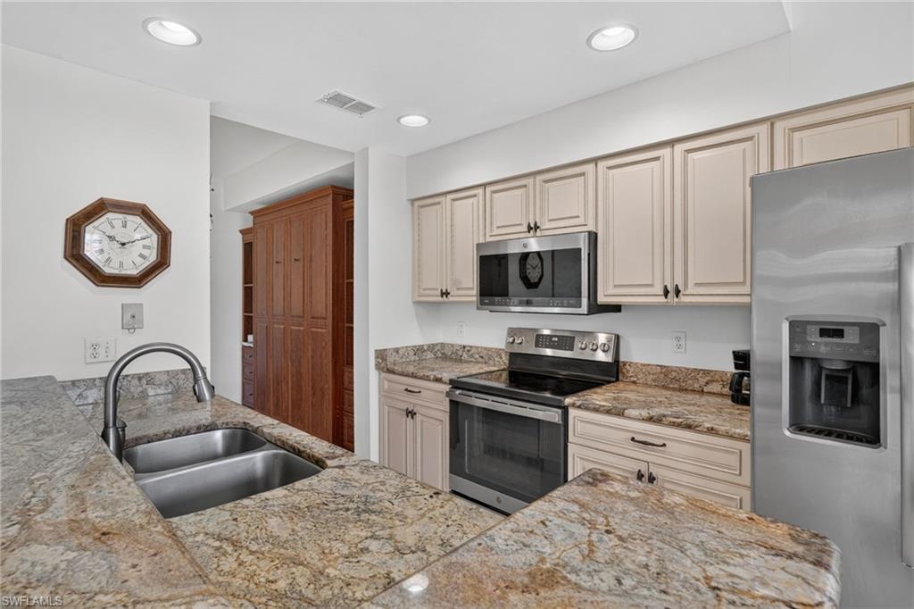 Kitchen featuring granite countertops, stainless steel appliances, dual basin sink, recessed lighting, and ample cabinetry