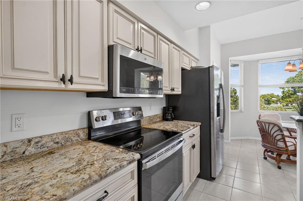 Kitchen featuring light-toned cabinetry, granite-finish countertops, stainless steel appliances, and tile flooring