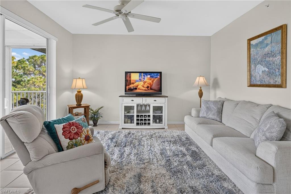 Living area featuring light-toned walls, tile flooring, and a ceiling fan