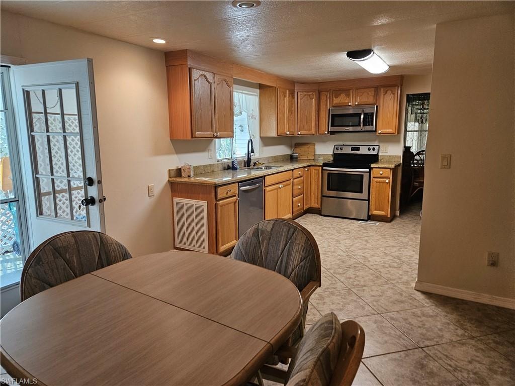 Kitchen with sink, appliances with stainless steel finishes, a textured ceiling, and light tile patterned floors