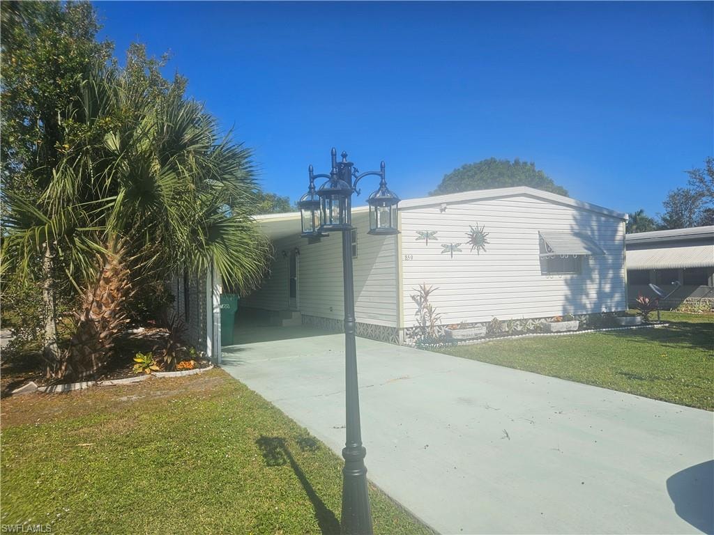 View of side of property featuring a yard, driveway, and a carport