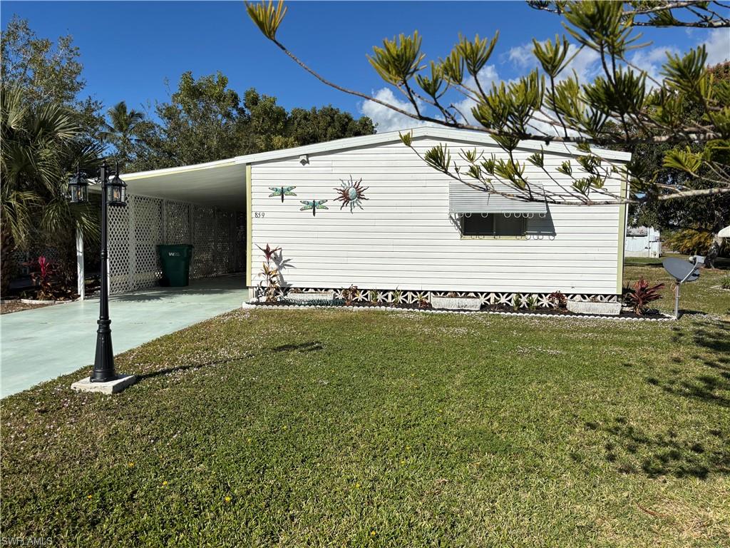 View of FRONT of home with driveway, a yard, and an attached carport