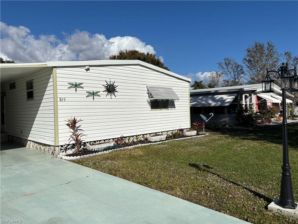 View of side of home featuring a lawn, driveway, and a carport