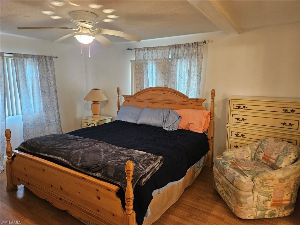 Bedroom with ceiling fan, wood-type flooring, and beam ceiling