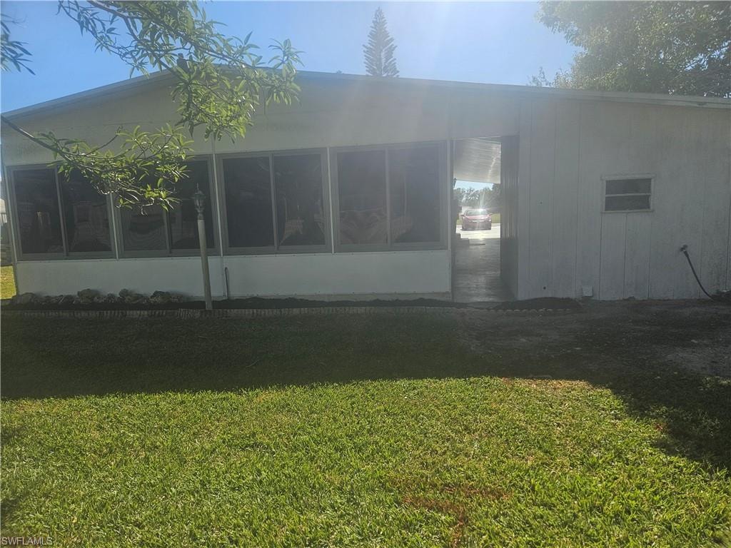 Back of house with a yard and a sunroom