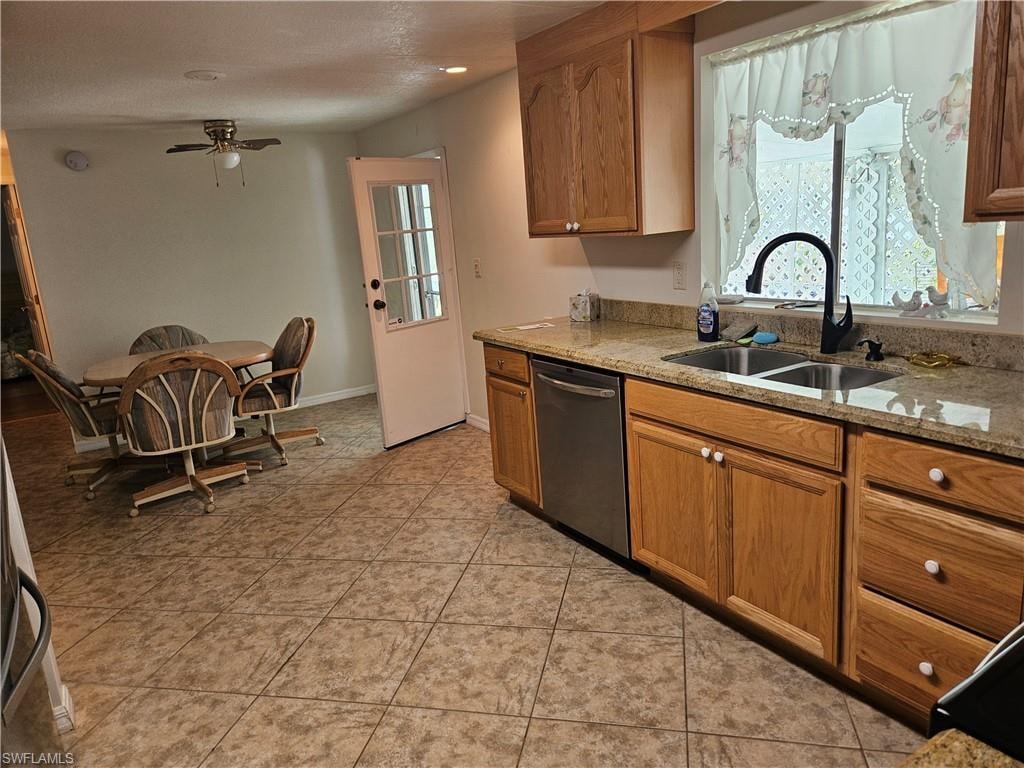 Kitchen with light stone countertops, sink, light tile patterned flooring, dishwasher, and ceiling fan
