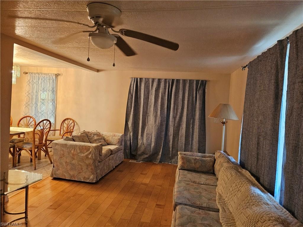 Living room featuring a textured ceiling, light wood-type flooring, and ceiling fan