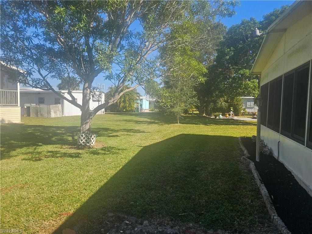 View of green lawn featuring a sunroom