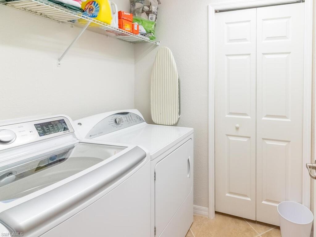 Clothes washing area featuring separate washer and dryer and light tile patterned floors