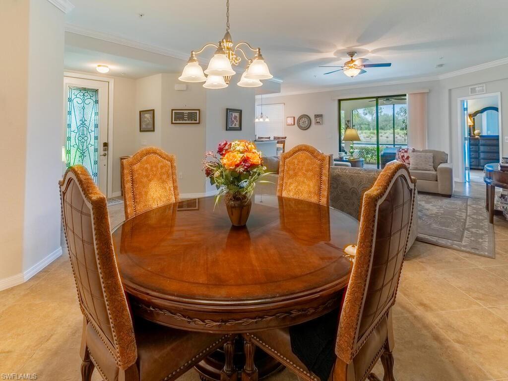 Dining space with ornamental molding, ceiling fan with notable chandelier, and light tile patterned floors