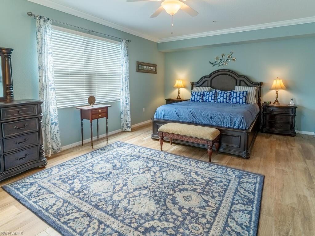 Bedroom with light hardwood / wood-style floors, crown molding, and ceiling fan