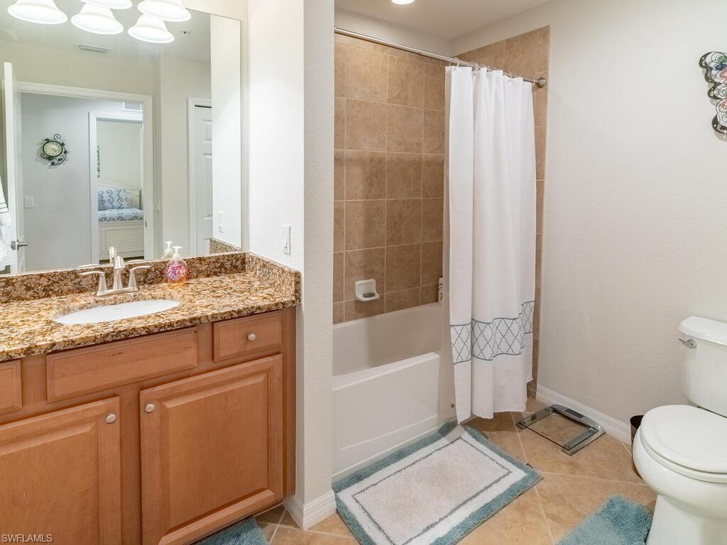 Full bathroom featuring vanity, shower / tub combo with curtain, toilet, and tile patterned flooring