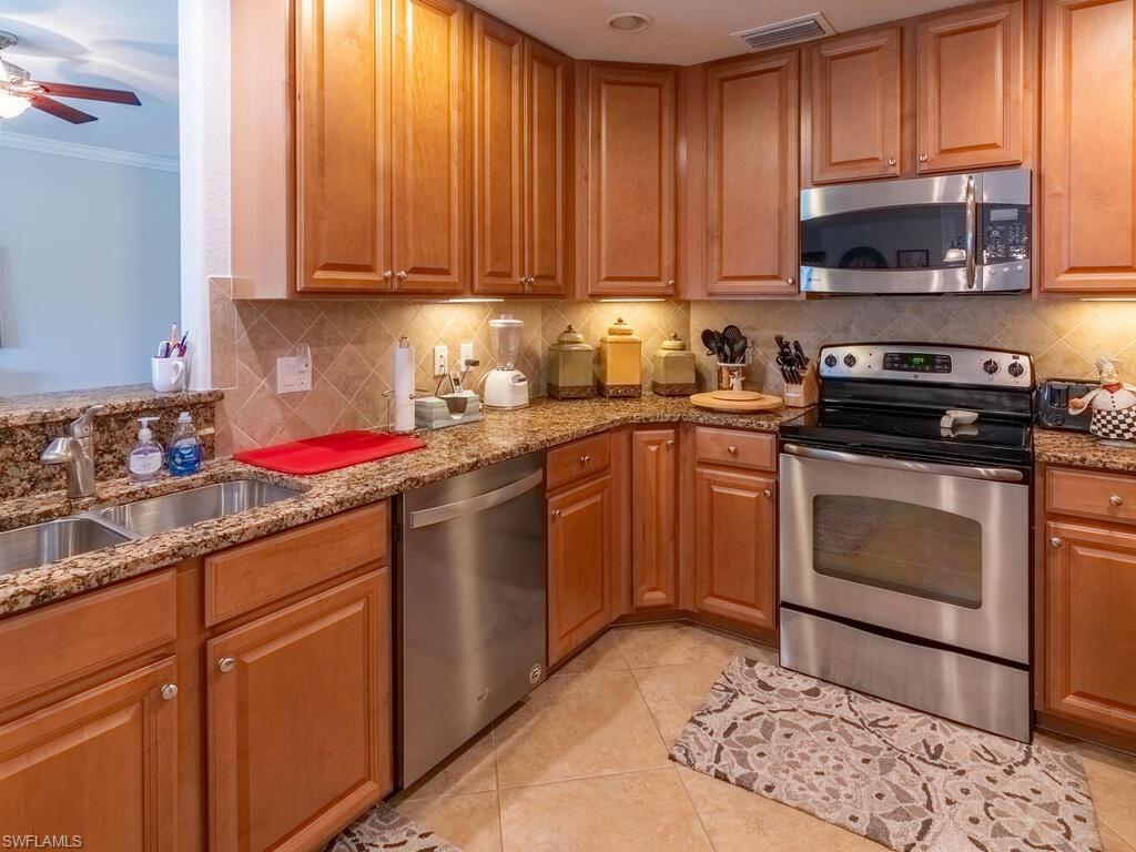 Kitchen featuring tasteful backsplash, light tile patterned floors, light stone countertops, crown molding, and stainless steel appliances