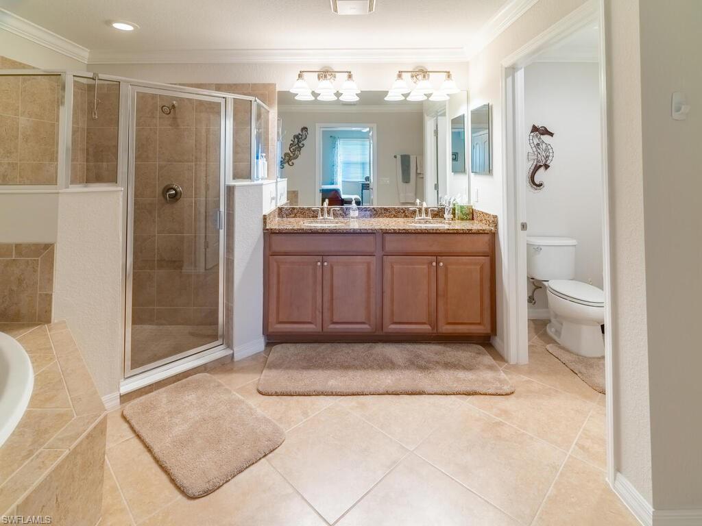 Full bathroom with vanity, toilet, independent shower and bath, and ornamental molding