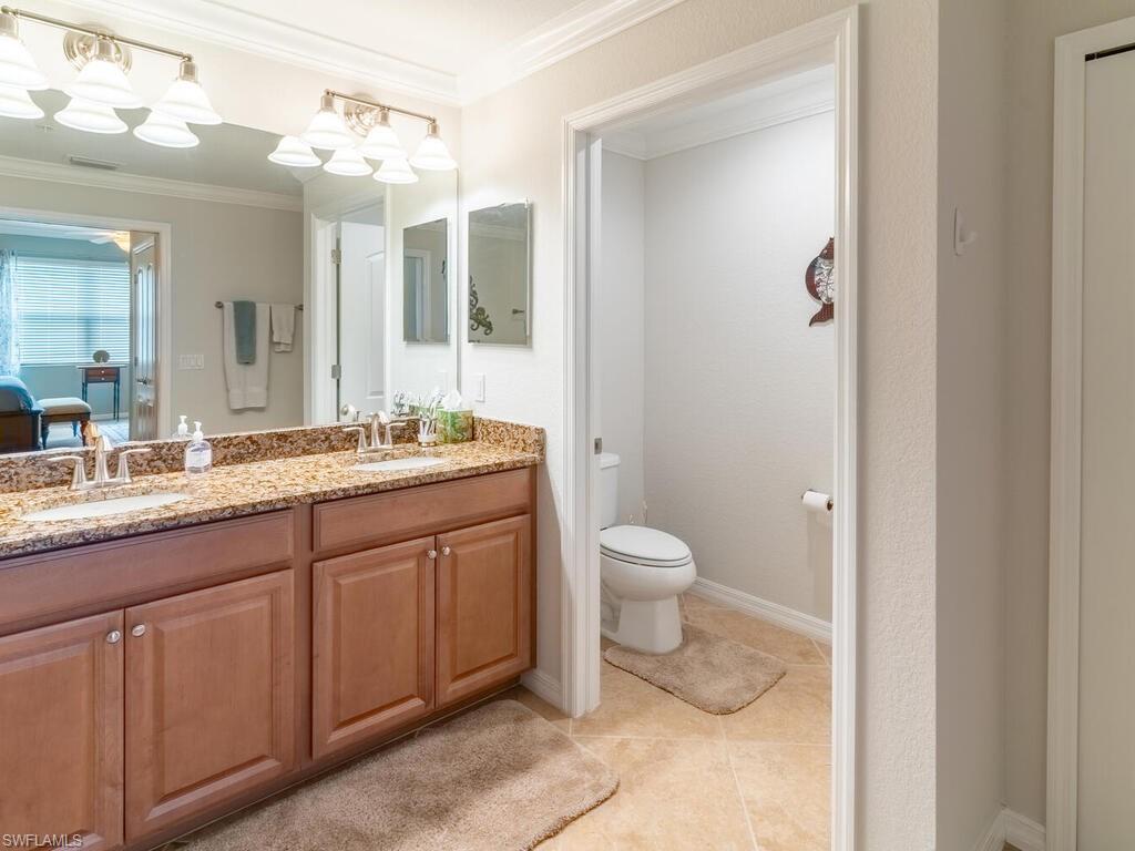 Bathroom with toilet, ornamental molding, vanity, and tile patterned flooring