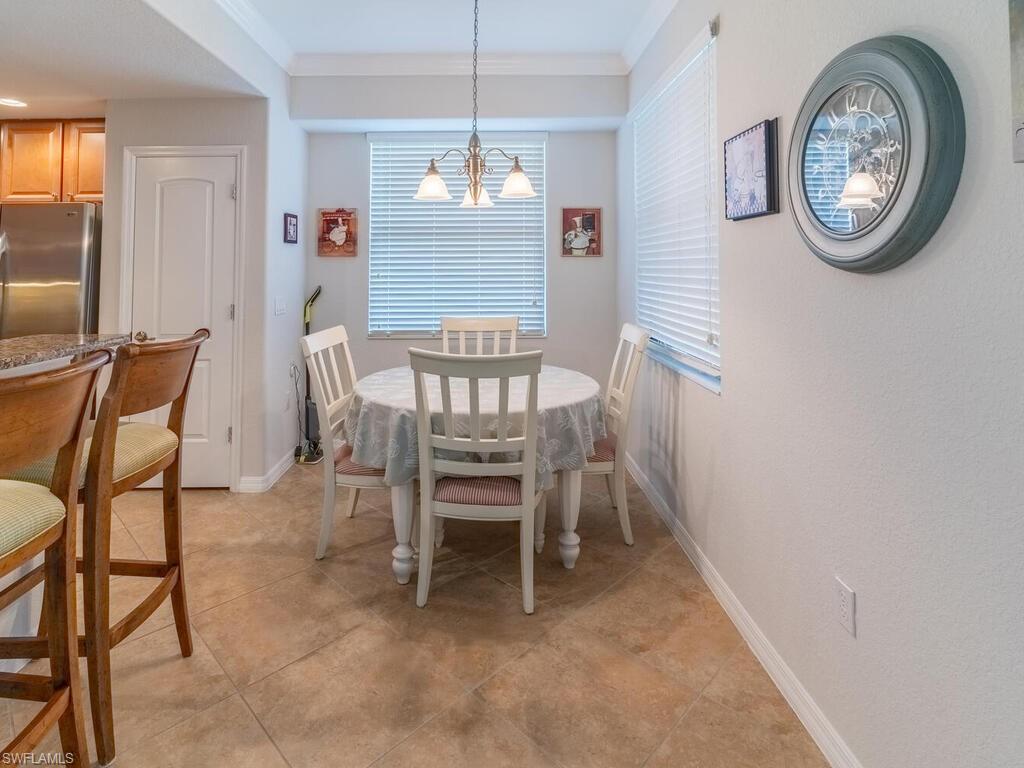 Tiled dining area featuring crown molding and an inviting chandelier