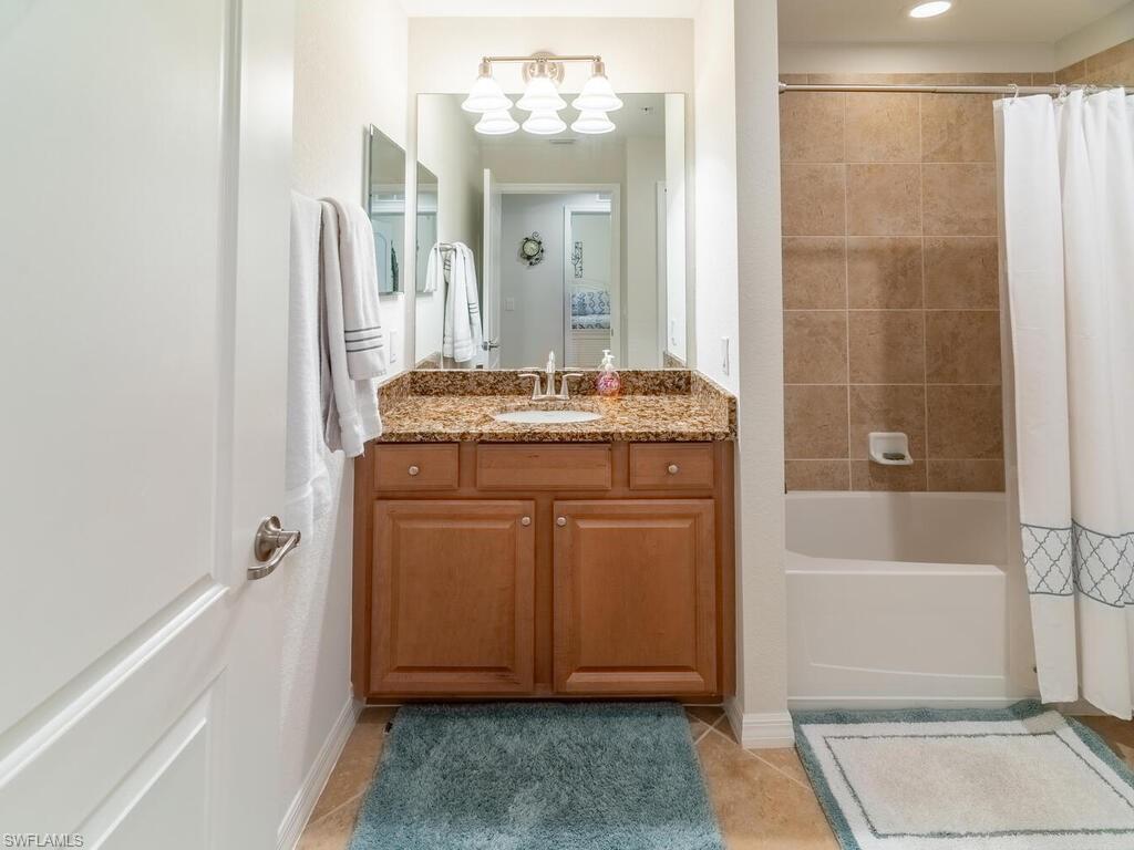 Bathroom featuring vanity, shower / tub combo with curtain, and tile patterned floors