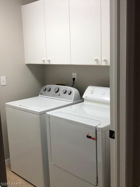 Dedicated laundry area featuring overhead white cabinetry for storage