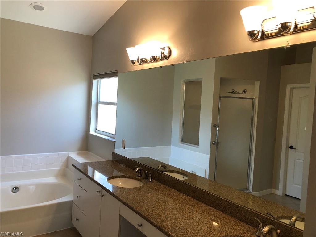 Bathroom featuring a dual vanity with a granite countertop, white cabinetry, and undermount sinks